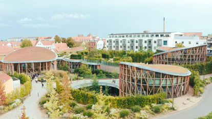 The distinct, modern, circular architecture of the Hans Christian Andersen House Museum in Odense, Denmark, surrounded by green landscaping.